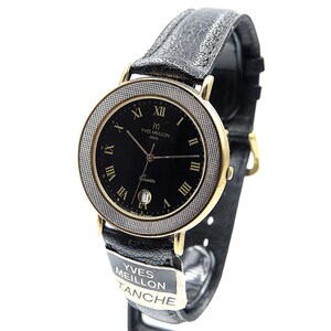 May include: A gold-toned Yves Meillon Paris quartz watch with a black dial and Roman numeral hour markers. The watch features a textured bezel and a black leather strap. The watch face displays the date. The watch is water resistant.