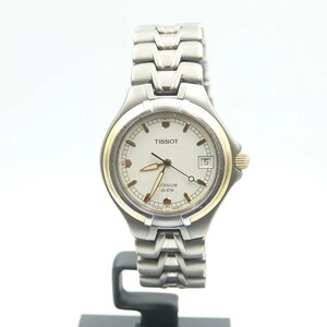 May include: A silver and gold Tissot wristwatch with a white face and a titanium band. The watch face has the words "Tissot" and "Titanium 100 meter" printed on it.