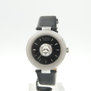 Puede incluir: Un reloj de pulsera Versus Versace con esfera negra, un emblema central de cabeza de le&oacute;n plateada y un bisel plateado texturizado. El reloj cuenta con una correa de cuero negro texturizado y herrajes plateados, con el nombre de la marca impreso.