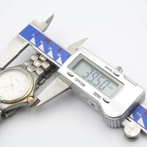 May include: A silver watch with a white face and a silver metal band is being measured with a digital caliper. The caliper reads 39.50 mm.