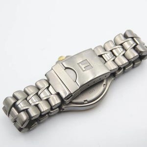 May include: A silver-toned wristwatch with a stainless steel band. The watch has a silver face and a silver buckle.