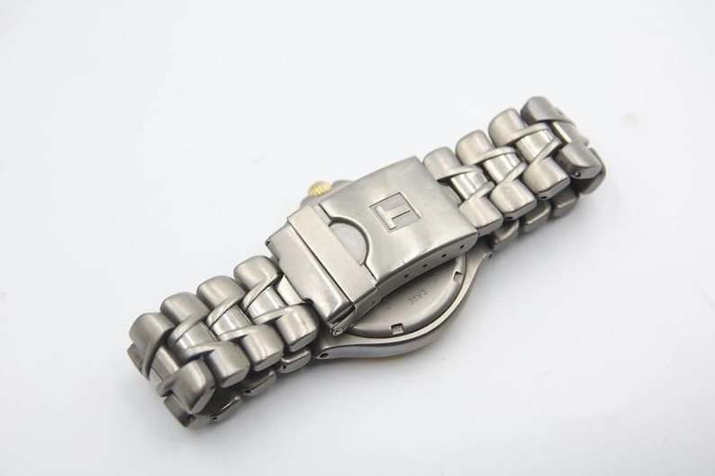 May include: A silver-toned wristwatch with a stainless steel band. The watch has a silver face and a silver buckle.