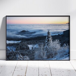Könnte beinhalten: Panoramablick auf einen schneebedeckten Wald mit einem einzelnen, hohen Nadelbaum im Vordergrund. Der Wald ist von einer dicken Nebelschicht bedeckt, im Hintergrund ein blauer Himmel mit rosafarbenen Wolken.