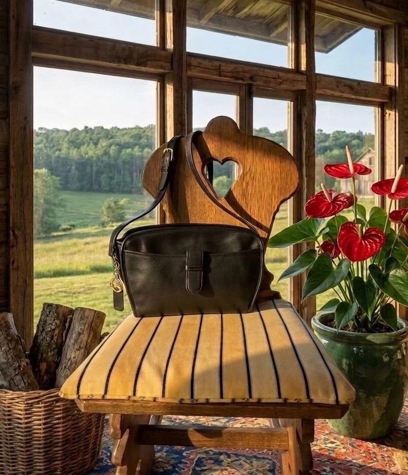 May include: A black leather crossbody bag with a buckle closure sits on a vintage chair with a striped cushion. The chair has a heart-shaped cutout in the back. A potted plant with red flowers is to the right, and a basket of logs is to the left.