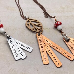 May include: Three necklaces with charms. The first necklace has a red and white mushroom charm and a silver charm with the words "Feed" and "Dad". The second necklace has a wooden leaf charm and five silver charms with the words "Such a long, long", "to be gone", "and a", "art time to be", and "there". The third necklace has a red and white mushroom charm and a silver rabbit charm and five silver charms with the words "Feed", "Dad", "a", "e", and "CL".