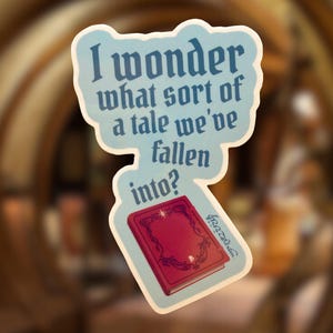 May include: A die-cut sticker with a light blue background featuring the dark blue text I wonder what sort of a tale we've fallen into? and a red book with gold filigree details and a small star icon on the front cover.