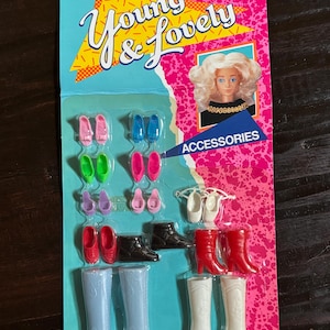 May include: A vintage doll accessories set on a pink and blue card. The set includes various pairs of shoes and boots in colours like pink, green, blue, red, black, and white. The packaging reads "Young & Lovely" and "Accessories".