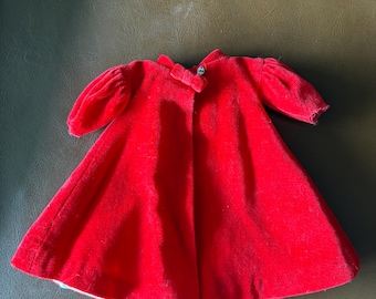 May include: A bright red velvet doll coat with short, puffed sleeves and a small collar. The coat has a flared skirt and a single button closure. The lining is white. This vintage doll coat is a classic piece.