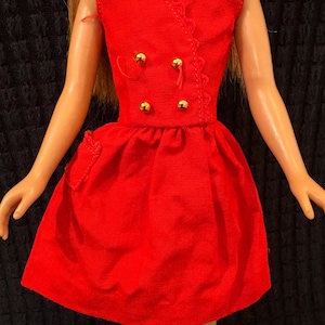 May include: A bright red sleeveless dress with a V-neckline featuring scalloped trim. The bodice has a double-breasted design with four small gold-toned spherical buttons. The skirt is gathered at the waist and includes a small side pocket.