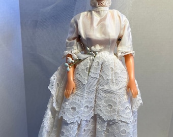 Barbie-Hochzeitskleid aus Satin (?) mit halben Ärmeln und Spitzenüberzug in Creme/Elfenbein. Mit Brauthut/Schleier. Ohne Tag. (Puppe nicht im Lieferumfang enthalten.)