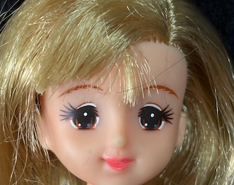 Muñeca Takara Jenny de los años 80, con rodillas articuladas y vestido rojo y blanco con etiqueta.