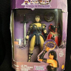 May include: A 10-inch tall action figure of Xena, Warrior Princess, from the popular television series. The figure is fully poseable and comes with accessories. The packaging features a purple background with the Xena logo and the words "Deluxe Edition".