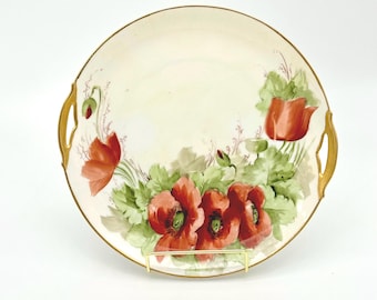 May include: A white porcelain serving platter with gold trim and two handles. The platter is decorated with hand-painted red poppies and green leaves.