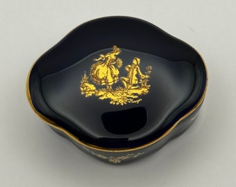 May include: A small, blue and gold trinket box with a raised design of a couple in a garden. The box is made of Limoges porcelain.