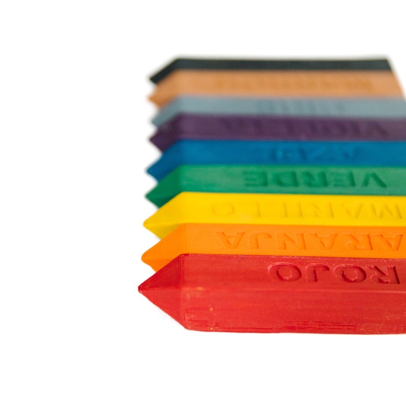 Puede incluir: Un conjunto de diez l&aacute;pices de colores dispuestos en orden de arco&iacute;ris, con las palabras "ROJO", "NARANJA", "AMARILLO", "VERDE", "AZUL", "VIOLETA", "MORADO", "GRIS", "MARR&Oacute;N" y "NEGRO" impresas en cada l&aacute;piz.