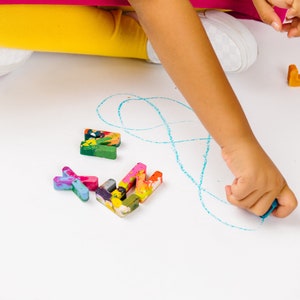 Image is of kids hands coloring with crayon letters. These custom crayons in the shape of rainbow crayon letters are a perfect holiday gift idea or stocking stuffer for children.