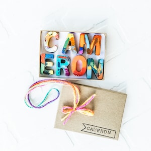 Image is of a 7-letter crayon name set, CAMERON, that comes in rainbow crayon letters. This ready to gift crayon name set comes personalized, making it a perfect birthday gift for kids or party favor for kid.