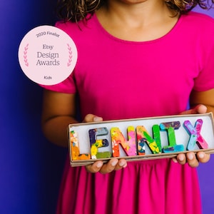 Personalized crayon names featuring Multi-colored crayons in ABC shapes. Crayon shop, Art 2 the Extreme, creates custom crayons in any name! Each crayon letter is easy to hold and features an array of bright colors that blend together.