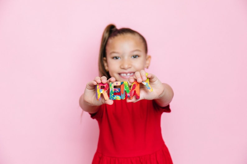 Image spells the name REMY in rainbow crayon letters. This is a perfect 2 year old gift or stocking stuffer for kid idea. Rainbow crayons also make great party favors.