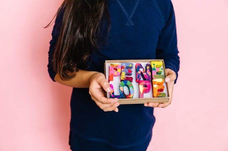 Image is a rainbow crayon name in letters that spell PENELOPE.  This custom crayon set is a perfect gift for a 2 year old. This personalized kids gift comes in a ready to gift box with name personalize on the outside.
