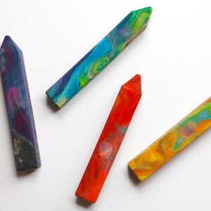 May include: Four crayons with a swirled, marbled design. The crayons are blue, red, green, and purple.