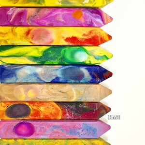 May include: A set of ten colorful crayons with a marbled effect. The crayons are arranged vertically, with the top crayon being yellow and the bottom crayon being yellow. The crayons are all different colors, including red, orange, yellow, green, blue, purple, and pink. The crayons are all about the same size and shape, and they are all pointed at one end. The text "ART 2 THE EXTREME" is visible on the bottom right corner of the image.