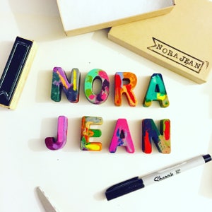 This custom crayon set spells the name NORA JEAN and comes in a ready to ship box. The child's name is personalized on the box and makes a great gift for a 2 year old.