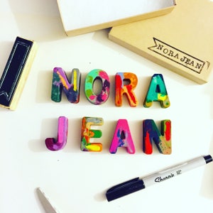 Multi-colored crayons in the letters of your name. Crayon shop, Art 2 the Extreme, creates custom crayons in any name! Each crayon letter features a mixture of bright colors, which blend together in endless combinations.