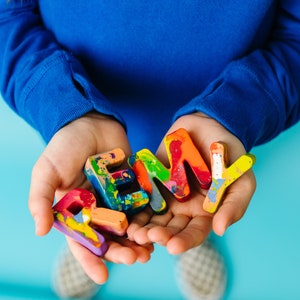 Name crayon set that spells the name REMY in a child's hands. This personalized kids gift is a great stocking stuffer gift or birthday gift for a 2 year old.
