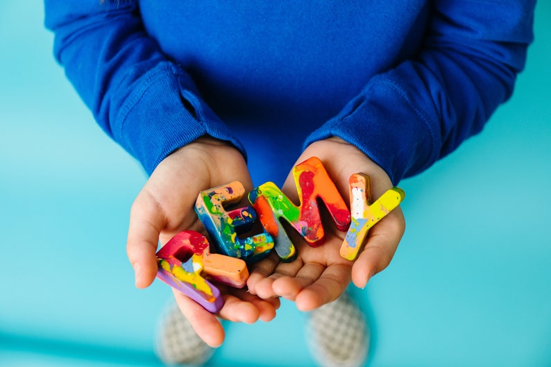 Name crayon set that spells the name REMY in a child's hands. This personalized kids gift is a great stocking stuffer gift or birthday gift for a 2 year old.