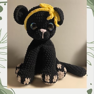 May include: A black crocheted panther with a yellow headband and large googly eyes. The panther is sitting on a white surface. The text "Luna the Panther Crochet pattern" is at the top and bottom of the image.