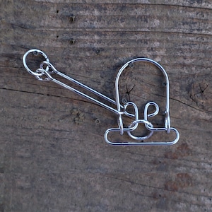 May include: A silver metal puzzle with a loop and a handle. The puzzle is made of multiple interlocking pieces.