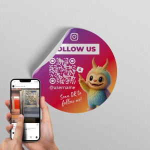 Op de afbeelding: Een ronde sticker met een verloop van paars naar rood, met het Instagram-logo en de tekst "FOLLOW US". Een cartoonfiguur wijst naar een QR-code en de tekst "Scan QR to follow us!". Een telefoon toont een foto.