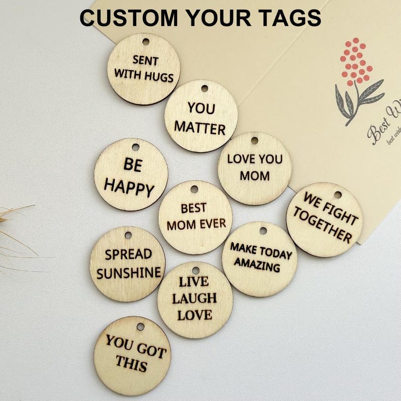 May include: A set of 11 round wooden tags with various inspirational messages, such as "You Matter", "Be Happy", "Spread Sunshine", and "Live Laugh Love".