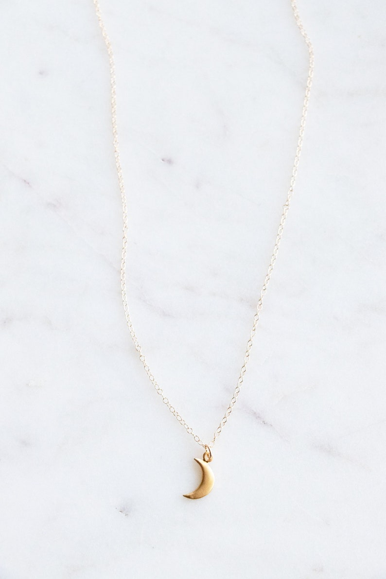 This dainty little gold moon charm dangles on an 18 inch 14k gold filled chain. Choose another tiny charm necklace in your favorite style if you like: mountains, heart, or puzzle.