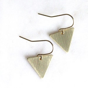 May include: A pair of gold triangle earrings with a brushed finish. The earrings have a simple, minimalist design.