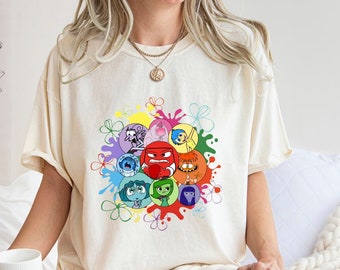 Könnte beinhalten: Ein weißes T-Shirt mit einem bunten Grafikdruck von Cartoon-Charakteren aus dem Film Inside Out. Die Charaktere sind in einem Kreis angeordnet, umgeben von einem Regenbogen aus Farben.