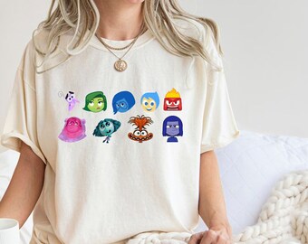 Könnte beinhalten: Ein weißes T-Shirt mit einem Grafikdruck der Figuren aus dem Film Inside Out. Die Figuren sind Freude, Traurigkeit, Angst, Wut, Ekel, Bing Bong und die anderen Figuren aus dem Film.