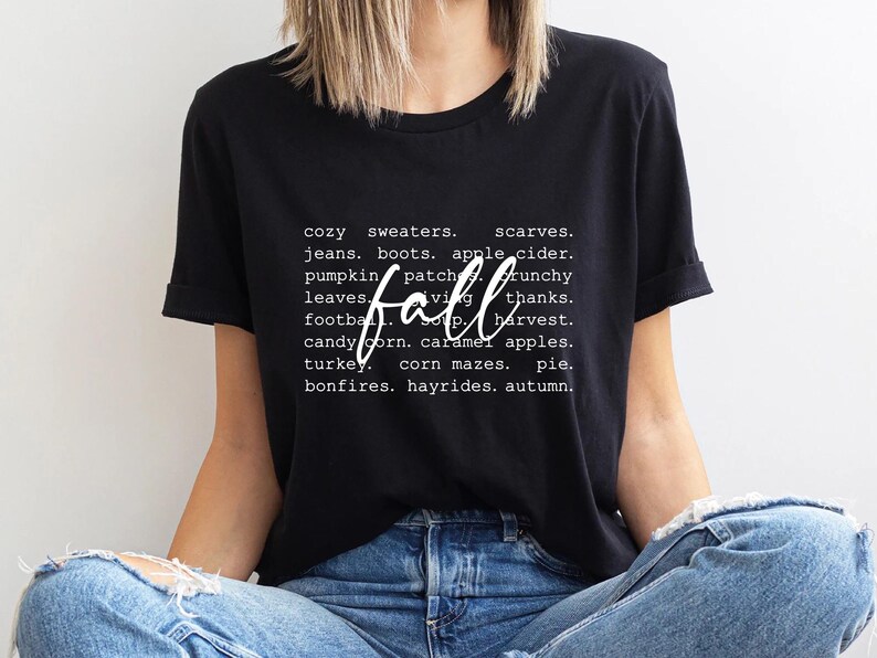 Może przedstawiać: Czarny T-shirt z białym tekstem, kt&oacute;ry brzmi "cozy sweaters. scarves. jeans. boots. apple cider. pumpkin patch. crunchy leaves. fall. thanks. football. soup. harvest. candy corn. caramel apples. turkey. corn mazes. pie. bonfires. hayrides. autumn."