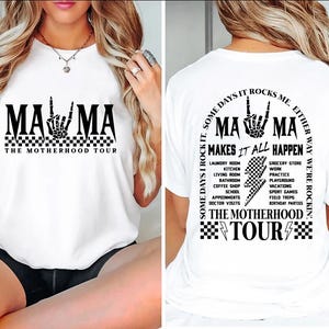 May include: White t-shirt with a black graphic that says "MAMA" with a hand gesture and "THE MOTHERHOOD TOUR". The back of the shirt has the same graphic and text, with additional text listing activities.