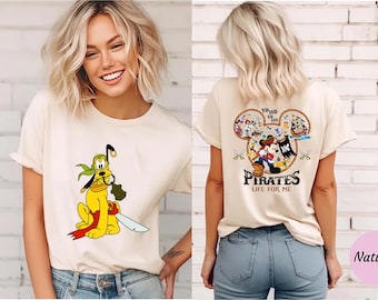 Könnte beinhalten: Cremefarbenes T-Shirt mit einem Cartoon-Pluto-Piraten mit einem Schwert. Auf der Rückseite des Shirts befindet sich ein Mickey-Mouse-Kopf-Design mit Piratenfiguren und dem Text "Pirates Life for Me."