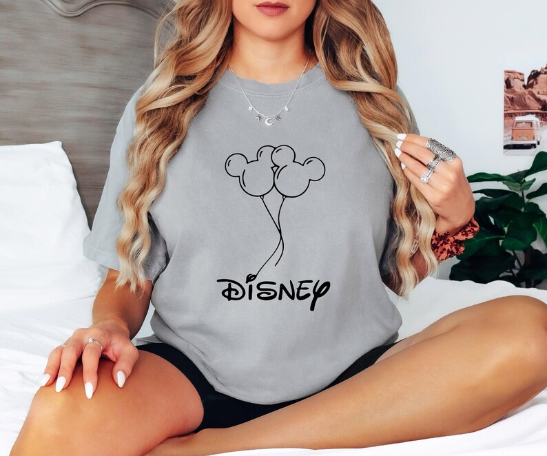 Może przedstawiać: Szary T-shirt z czarnym nadrukiem przedstawiającym balony w kształcie uszu Myszki Miki i napisem "DISNEY" poniżej.