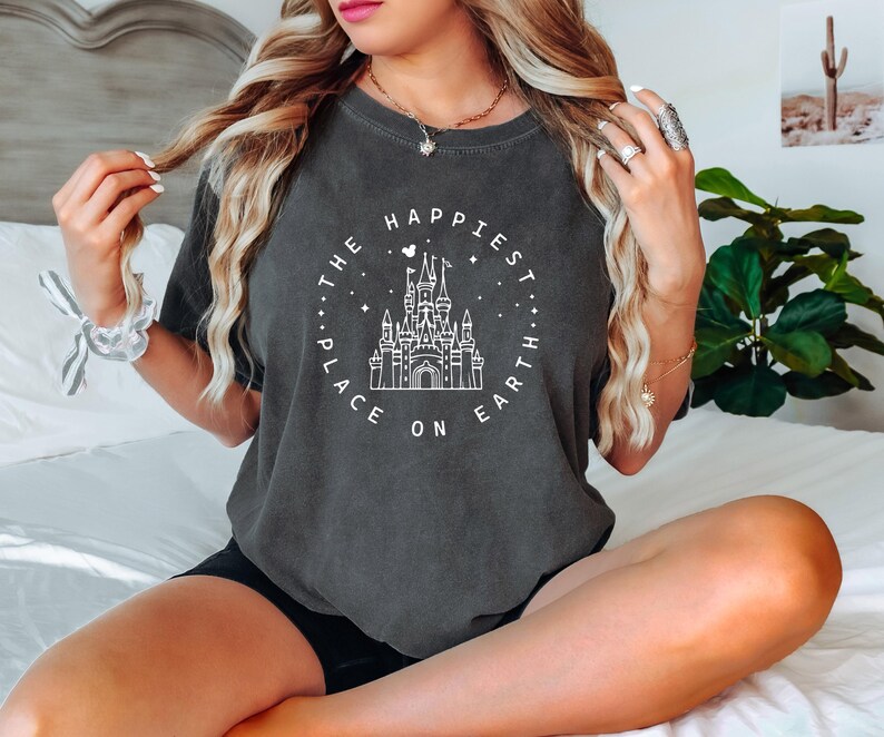 May include: A dark gray t-shirt with a white graphic of Cinderella's castle and the text "The Happiest Place on Earth".
