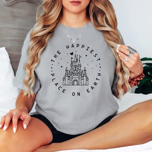 May include: A gray t-shirt with a black graphic of Cinderella's castle and the text "The Happiest Place On Earth".