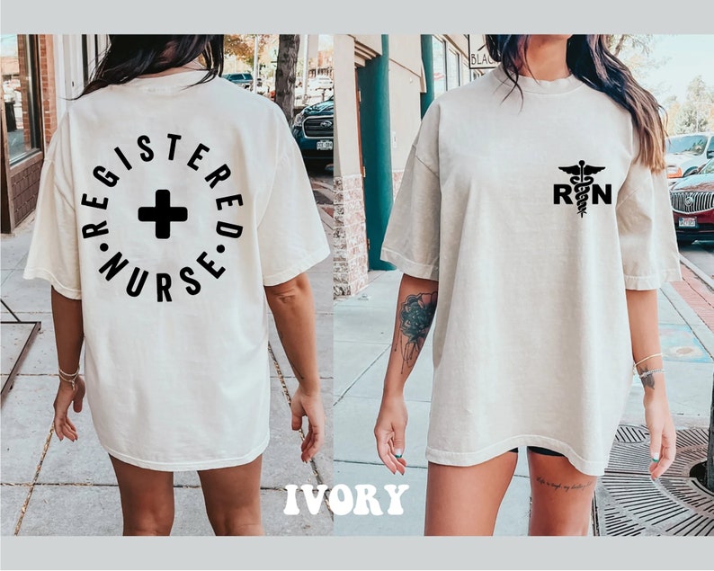 May include: A white oversized t-shirt with a black graphic on the back that says "Registered Nurse" in a circle with a plus sign in the center. The front of the shirt has a black graphic of a caduceus with the letters "RN" below it.