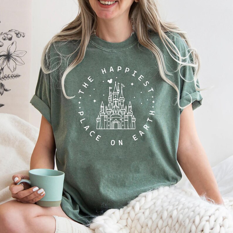May include: A green t-shirt with a white graphic of Cinderella's castle and the text "The Happiest Place On Earth".