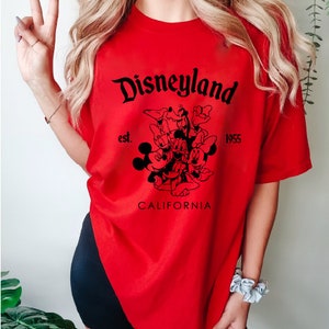 May include: Red t-shirt with a black graphic of Mickey Mouse and friends. The graphic includes the text "Disneyland est. 1955 California".
