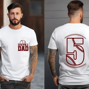 Könnte beinhalten: Weißes T-Shirt mit einem roten Baseball-Motiv und dem Text "Baseball Dad". Die Rückseite des Shirts hat eine rote Nummer 5 mit einem Baseball-Stich-Design.