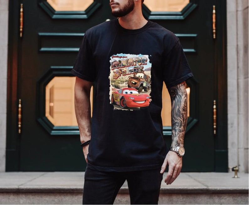 May include: Black t-shirt with a graphic print of Lightning McQueen and Mater from the movie Cars. The graphic includes the text "Radiator Springs" and "Greetings from".