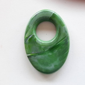 May include: A green oval-shaped pendant with a hole in the center. The pendant has a marbled pattern with swirls of green and white.